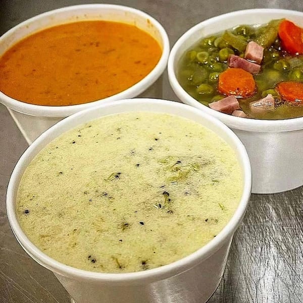 Three cups of soup: tomato, pea with ham and carrots, and a creamy green soup.