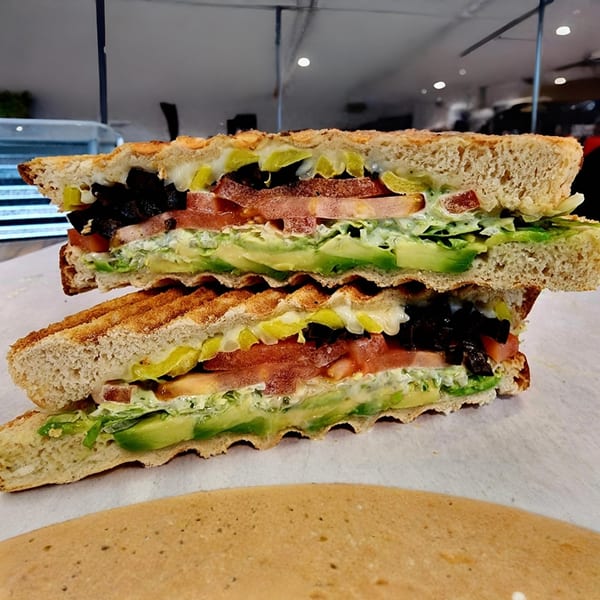 A toasted sandwich from Yellow Mustard, cut in half, revealing avocado, tomato, and other fillings.